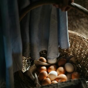 Close-up of a wicker basket filled with fresh farm eggs indoors, in rustic lighting.