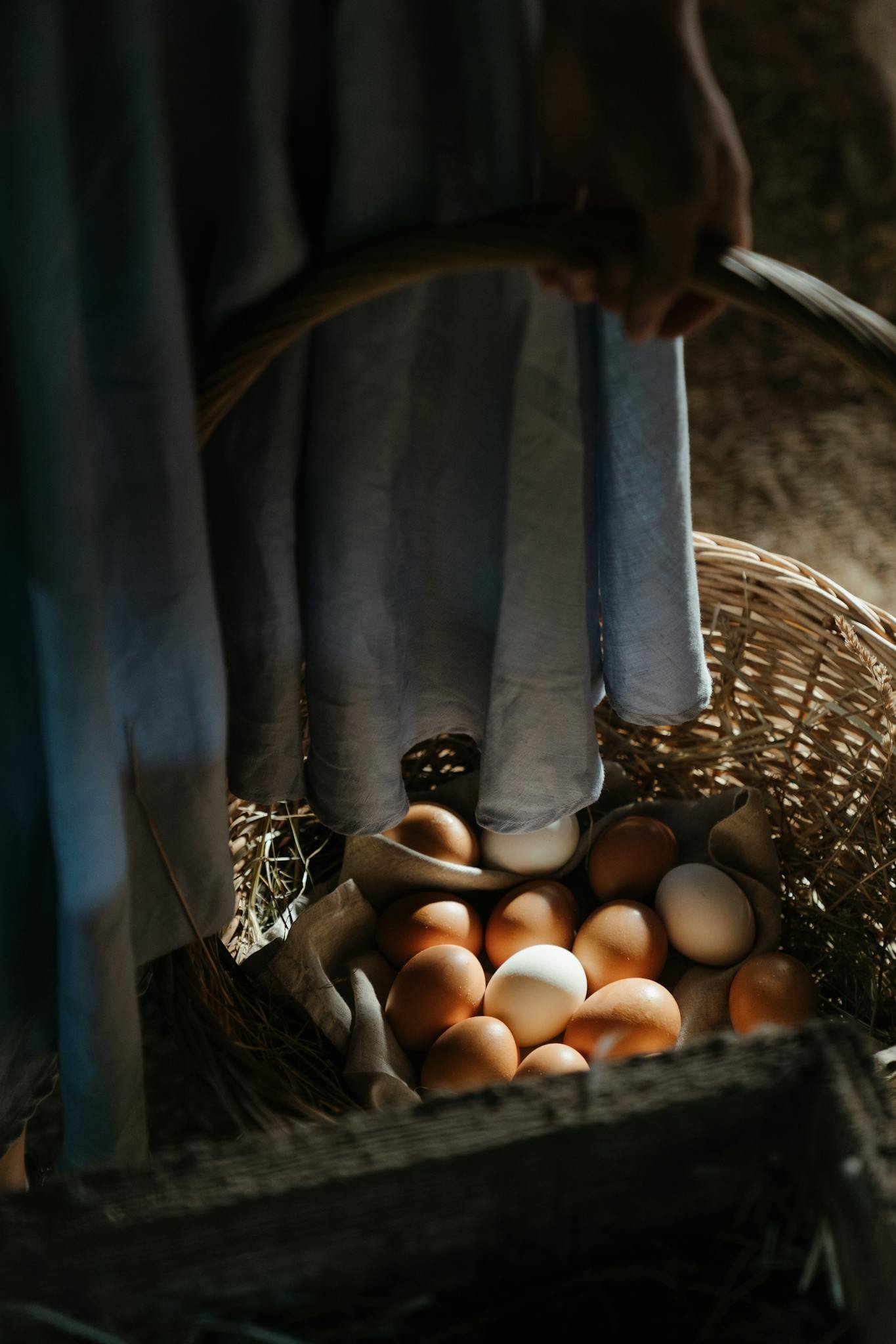 Close-up of a wicker basket filled with fresh farm eggs indoors, in rustic lighting.